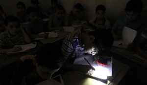 A student wears a headlight, due to electricity shortage, as he takes his year-end examinations at a school in Aleppo's al-Sha'ar district